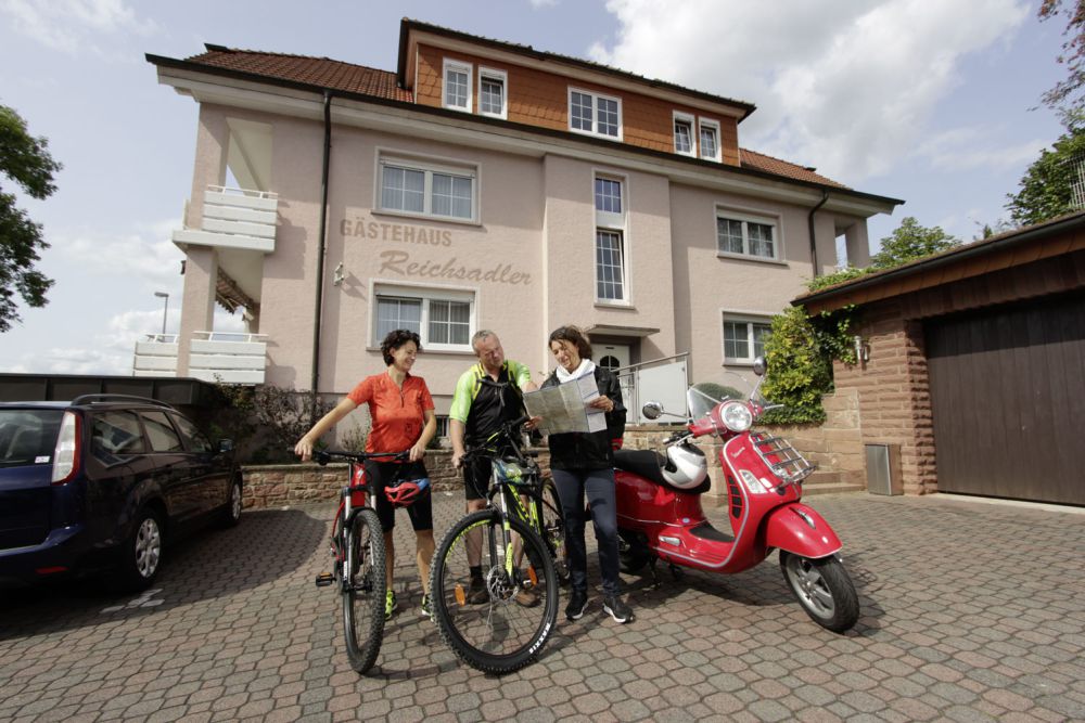 Fahrrad- und Rollerfahrer im Hof des Reichsadler Areals mit einer Wegkarte